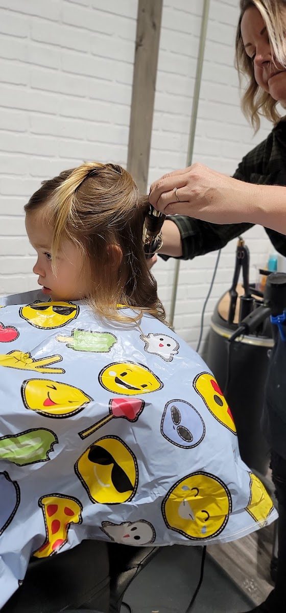 A stylist working on a young client&rsquo;s hair